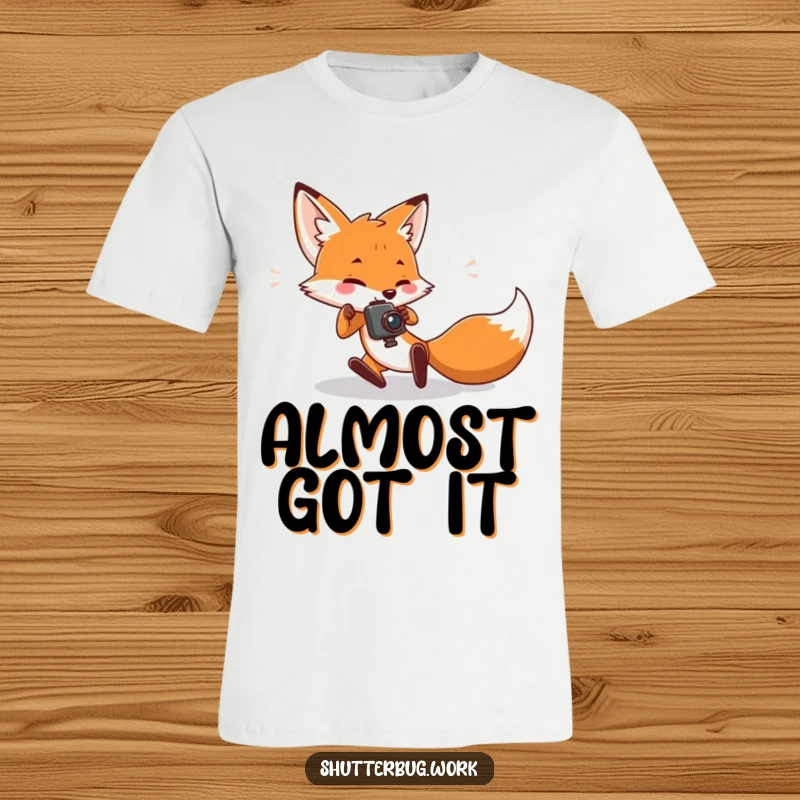 Funny T-Shirt showing a fox character hilariously tripping while holding a camera, capturing the funny side of pursuit for the perfect picture.